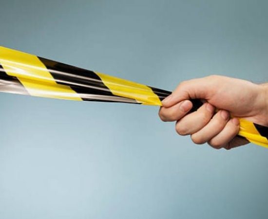 Mano agarrando una cinta de balizamiento a doble color amarilla y negra